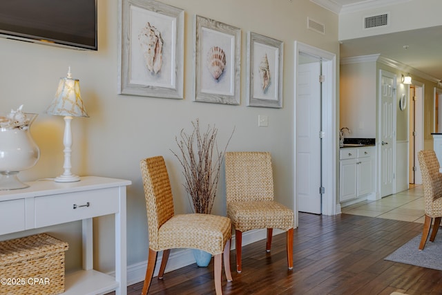 living area with visible vents, crown molding, baseboards, and wood finished floors