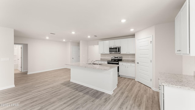 kitchen with a sink, stainless steel appliances, light wood-type flooring, and white cabinets