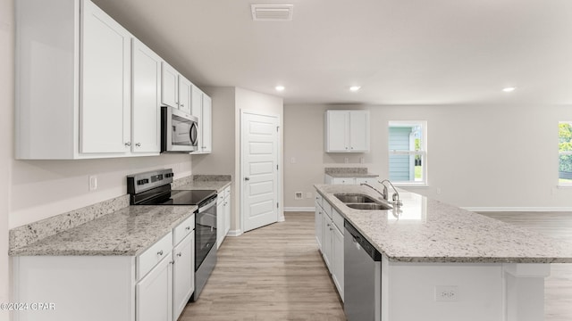 kitchen with visible vents, an island with sink, a sink, white cabinetry, and stainless steel appliances