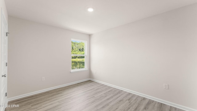 spare room with baseboards and light wood finished floors