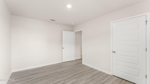 unfurnished room featuring recessed lighting, visible vents, light wood-style flooring, and baseboards