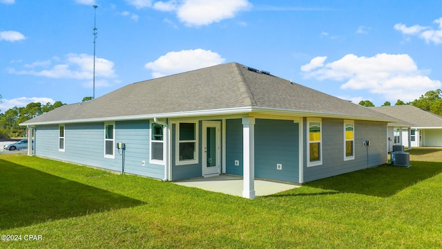 rear view of property with a yard, central air condition unit, roof with shingles, and a patio area