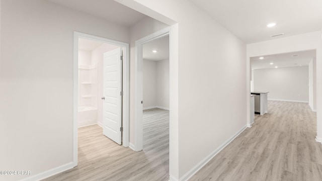 hallway featuring recessed lighting, baseboards, and light wood-style flooring