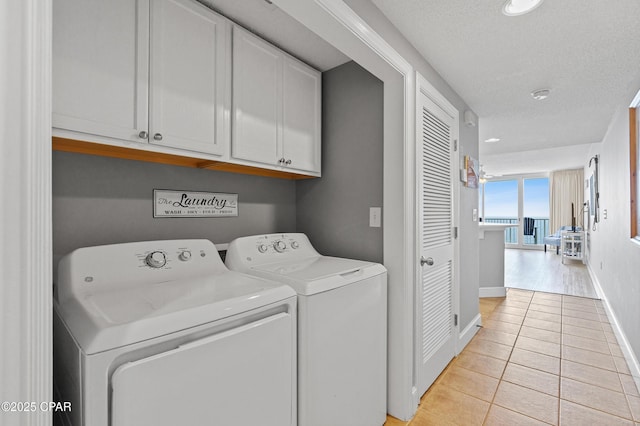 washroom with baseboards, light tile patterned floors, cabinet space, a textured ceiling, and separate washer and dryer