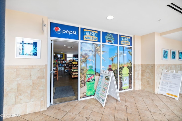 doorway to outside with a wainscoted wall, tile walls, and tile patterned flooring