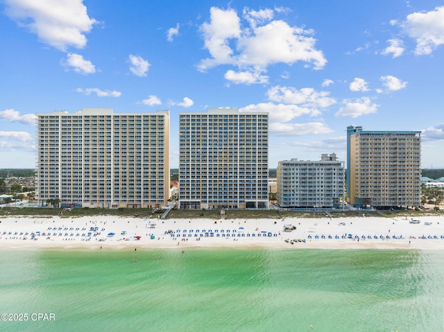 drone / aerial view featuring a water view, a city view, and a beach view