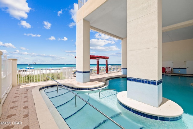 pool featuring a water view, a patio, and a view of the beach