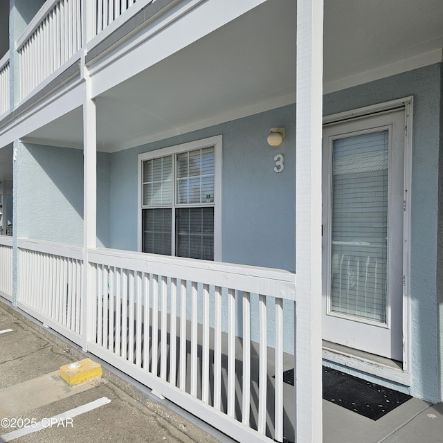 doorway to property featuring a porch and stucco siding