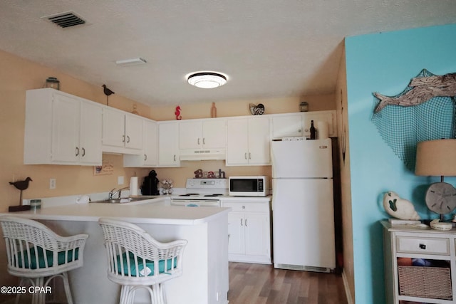 kitchen featuring sink, kitchen peninsula, white appliances, light hardwood / wood-style floors, and white cabinets