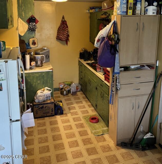 kitchen with green cabinets and white fridge