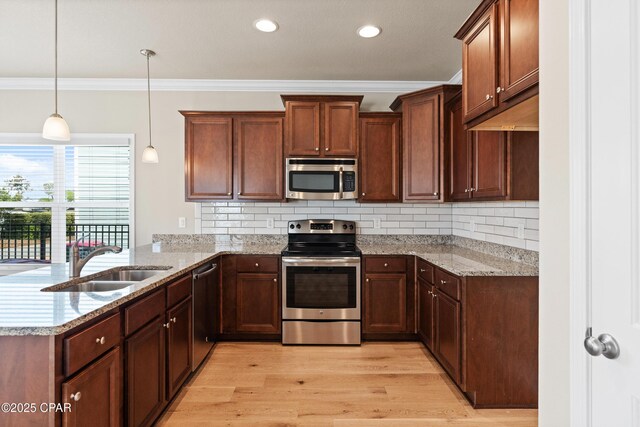 kitchen with a sink, ornamental molding, appliances with stainless steel finishes, light wood-style floors, and a peninsula