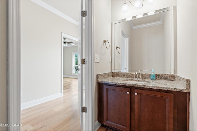 bathroom featuring crown molding, baseboards, vanity, and wood finished floors