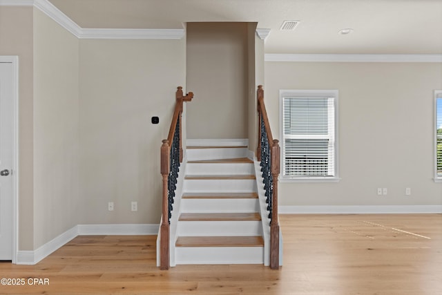 stairs with wood finished floors, baseboards, and ornamental molding
