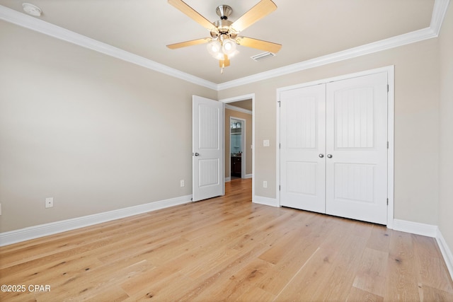 unfurnished bedroom featuring a closet, light wood finished floors, baseboards, and ornamental molding