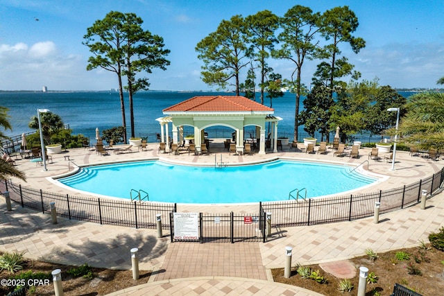 pool with a gazebo, a patio area, fence, and a water view