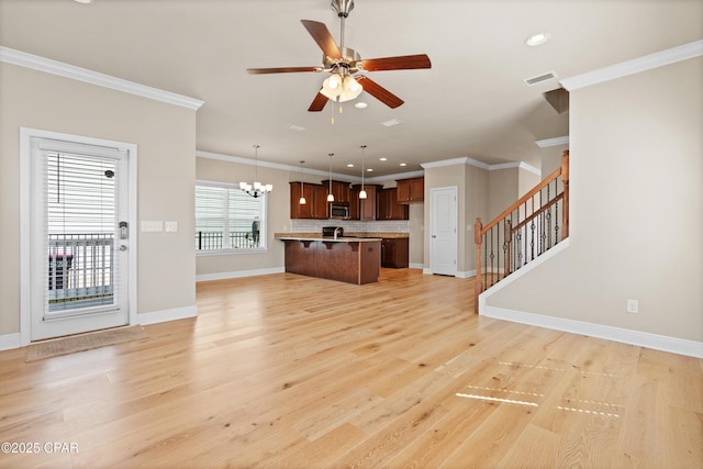 unfurnished living room with visible vents, baseboards, light wood-style floors, crown molding, and ceiling fan with notable chandelier