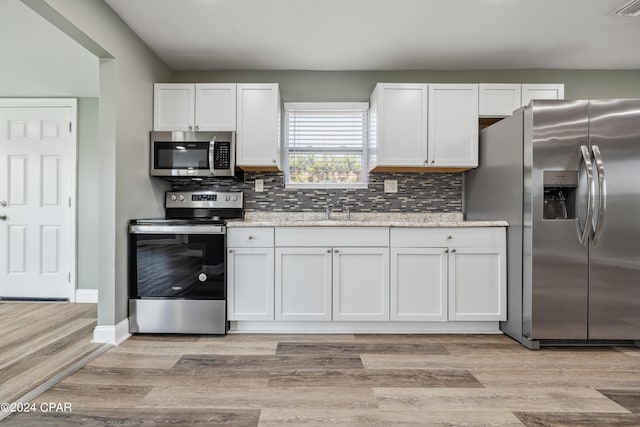 kitchen featuring stainless steel appliances, light stone countertops, and white cabinets