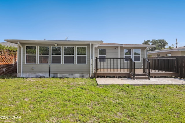 rear view of house featuring a wooden deck, fence, and a yard