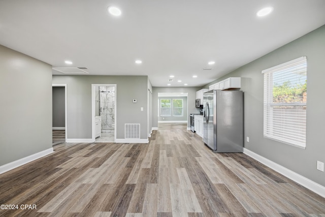 kitchen with light wood-style flooring, white cabinetry, stainless steel appliances, and baseboards