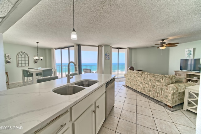 kitchen featuring white cabinets, open floor plan, decorative light fixtures, a sink, and stainless steel dishwasher