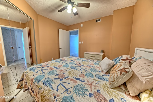 bedroom featuring light tile patterned floors, a textured ceiling, visible vents, a ceiling fan, and a closet