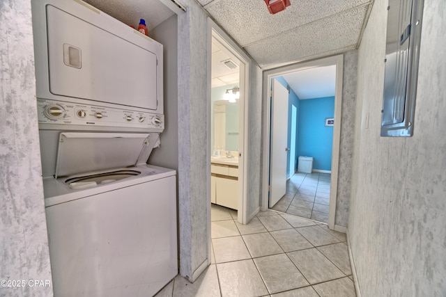 laundry area featuring light tile patterned floors, laundry area, stacked washer / dryer, and visible vents