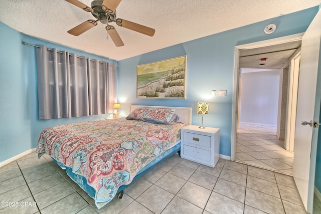 bedroom featuring ceiling fan, a textured ceiling, baseboards, and tile patterned floors