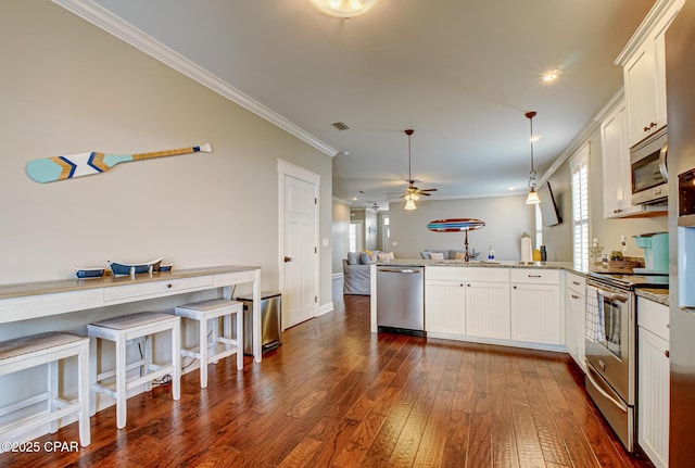 kitchen featuring white cabinetry, light stone counters, kitchen peninsula, pendant lighting, and stainless steel appliances