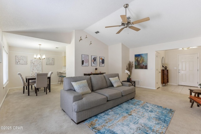 living room with vaulted ceiling, ceiling fan with notable chandelier, visible vents, and light carpet