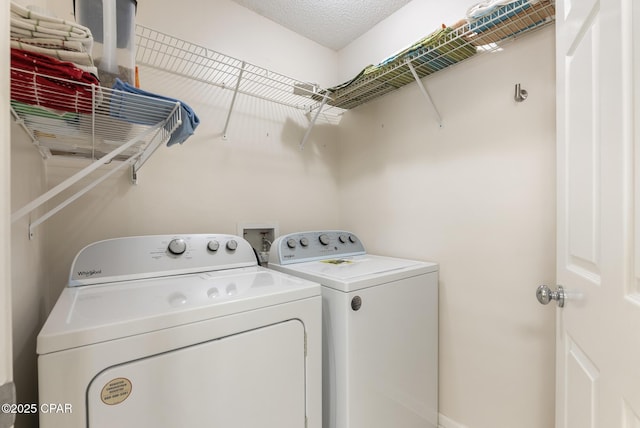 washroom with washer and dryer, a textured ceiling, and laundry area