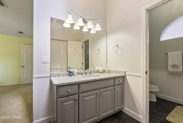 bathroom featuring visible vents, a wainscoted wall, toilet, tile patterned floors, and vanity