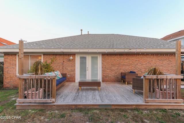 back of property featuring brick siding and roof with shingles