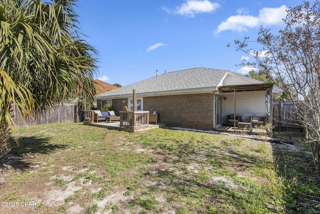 back of house with a yard, a deck, brick siding, and a fenced backyard