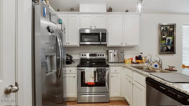 kitchen featuring light stone counters, sink, stainless steel appliances, and white cabinets