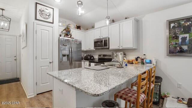 kitchen featuring appliances with stainless steel finishes, a kitchen breakfast bar, kitchen peninsula, and hanging light fixtures