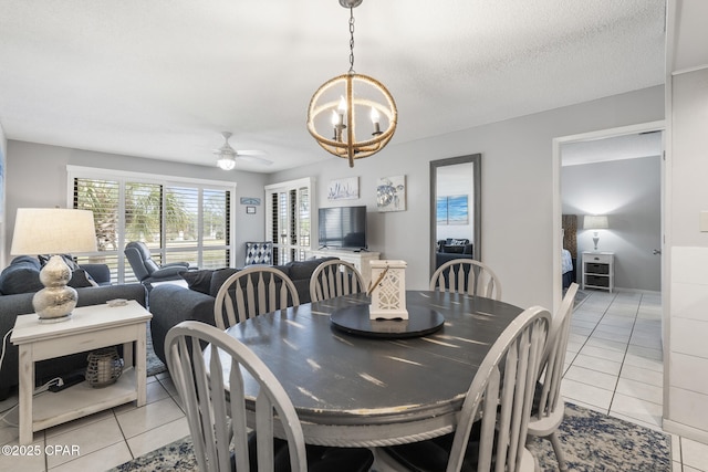 tiled dining space with ceiling fan with notable chandelier and a textured ceiling