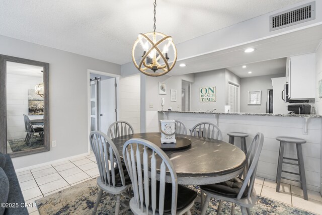 tiled dining space with a notable chandelier and a textured ceiling