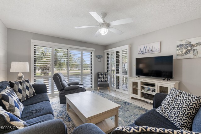 living room featuring light tile patterned flooring, ceiling fan, and a textured ceiling