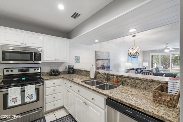 kitchen with sink, light tile patterned floors, appliances with stainless steel finishes, white cabinets, and dark stone counters