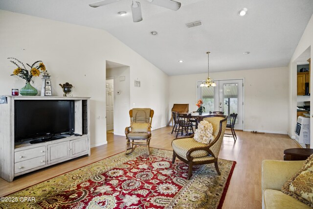 living room with lofted ceiling, ceiling fan, and light wood-type flooring