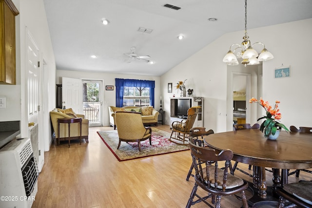 dining room featuring heating unit, ceiling fan with notable chandelier, light hardwood / wood-style flooring, and lofted ceiling