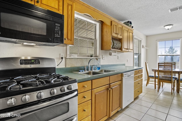 kitchen with sink, stainless steel gas stove, a textured ceiling, light tile patterned floors, and white dishwasher