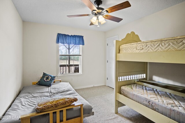 carpeted bedroom featuring ceiling fan and a textured ceiling