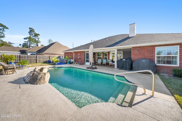 view of swimming pool with a patio area, a grill, fence, and a fenced in pool