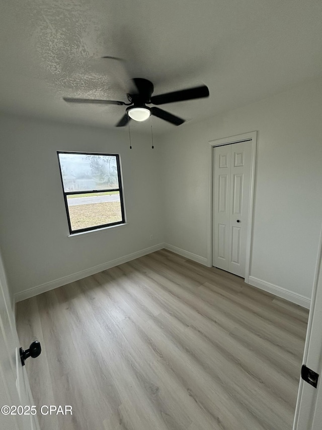 unfurnished bedroom with a textured ceiling, ceiling fan, and light hardwood / wood-style flooring