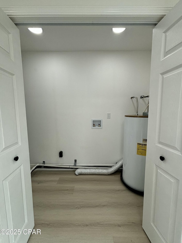 laundry room featuring water heater, light hardwood / wood-style flooring, and hookup for a washing machine