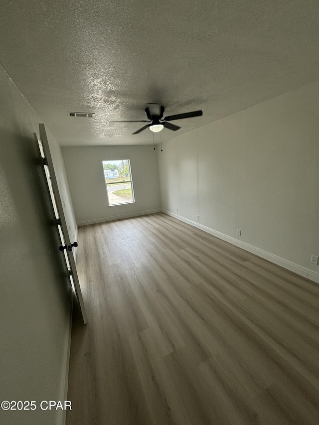 unfurnished room featuring ceiling fan, wood-type flooring, and a textured ceiling