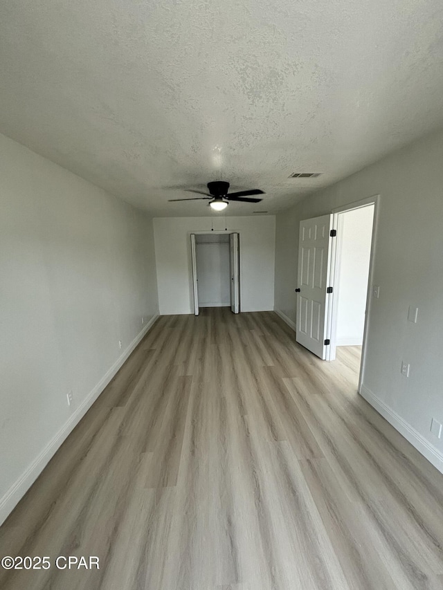 interior space with ceiling fan, light wood-type flooring, and a textured ceiling