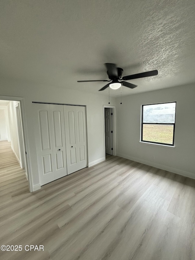 unfurnished bedroom featuring ceiling fan, light hardwood / wood-style flooring, a textured ceiling, and a closet