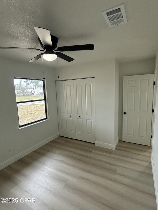 unfurnished bedroom featuring ceiling fan, light hardwood / wood-style flooring, and a closet